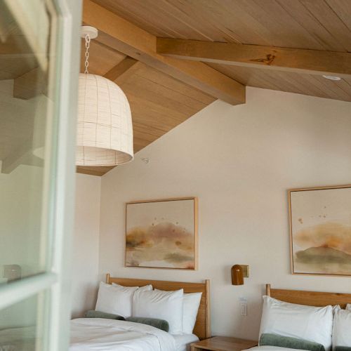 A cozy, sunlit bedroom with a white bed, wooden shelves, and soft, warm decor. Top it at 140 characters, always ending the sentence.