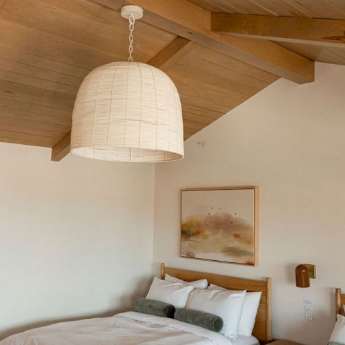 A cozy kitchen with warm wood beams, light cabinetry, and a white range hood; soft, rustic charm.