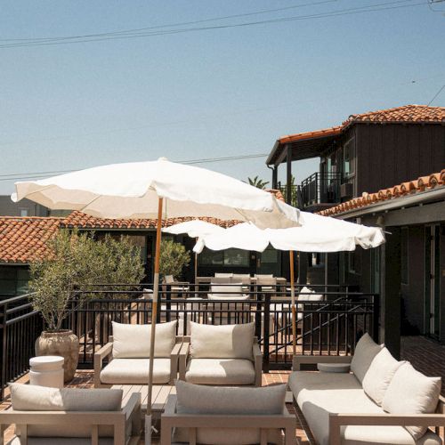 A sunny outdoor restaurant along a canal, with tables, umbrellas, and a brick building in the background.