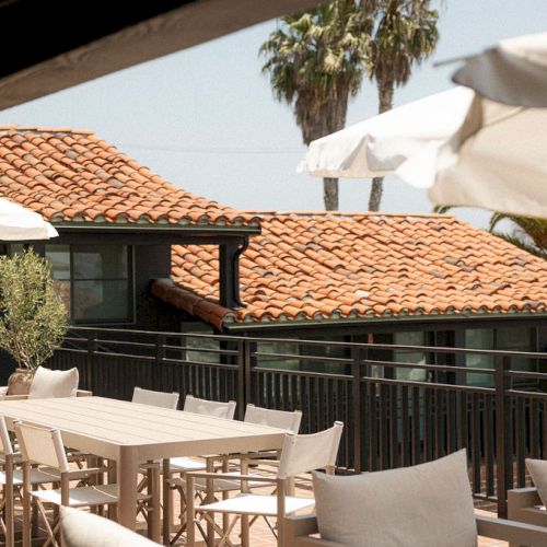 A sunny outdoor cafe with patio seating under striped awnings, palm trees, and a bright, relaxed seaside vibe. End.